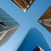 Looking up at four buildings, making an X in negative space in the sky.