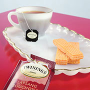 Teacup and plate, with cookies and a ripped teabag package.