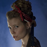 Girl with cigarette behind ear and bandana holding a baseball bat.